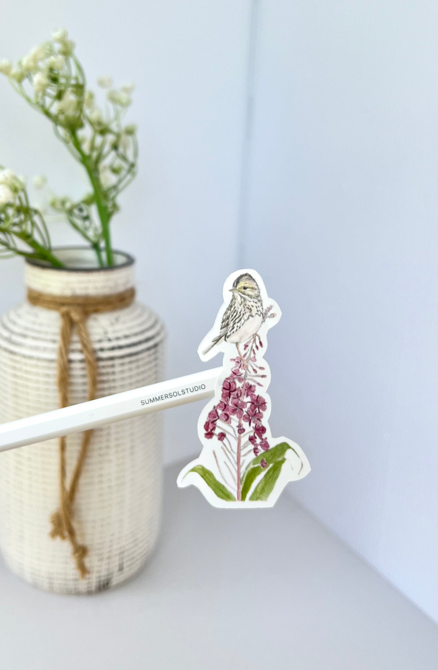A chickadee perched on top of a fireweed stalk.