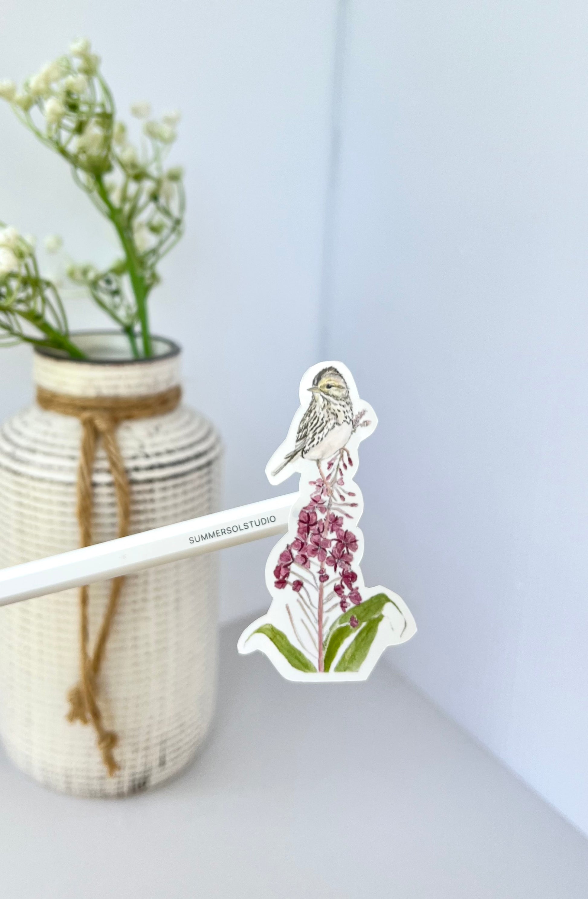 A chickadee perched on top of a fireweed stalk.